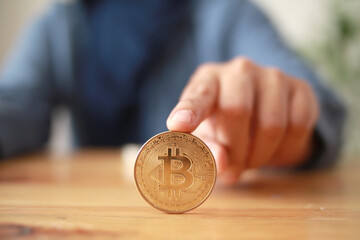 A person rolling bitcoin coin cryptocurrency on table, digital asset investment