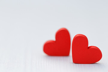 Two small red hearts made of wooden on bright white lights bokeh background. Valentine day background