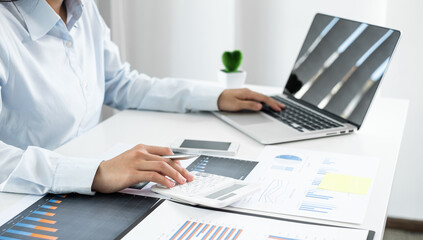 Asian female accountant sits at their desks and calculates financial graphs showing results about...