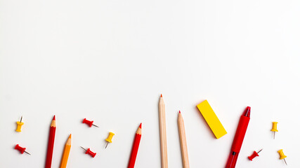 Red and yellow pen, sticky note, notepad, marker, eraser, push pins, paper clip pencils on the bottom on white background flat lay top view Education back to school online study concept copy space