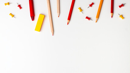 Red and yellow pen, sticky note, notepad, marker, eraser, push pins, paper clip pencils on the top on white background flat lay top view Education back to school online study concept with copy space