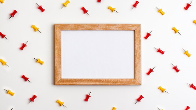 Yellow red push pins and wooden frame on white background. Flat lay top view. Education back to school and online study concept with copy space