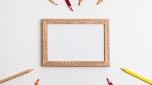 Yellow red pencils and wooden frame on white background. Stop motion animation flat lay top view. Education back to school and online study concept with copy space