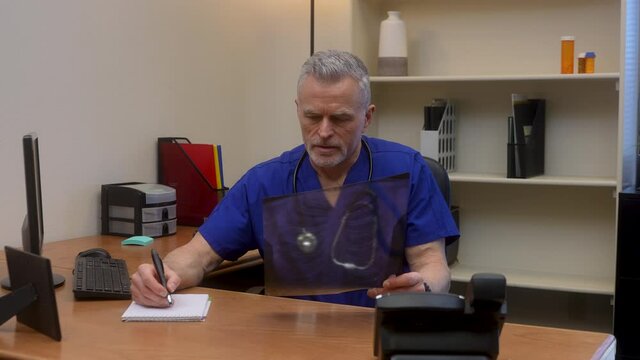 Worried doctor examines chest x-ray then looks at camera and shakes his head. Bad diagnoses