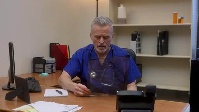 Angry doctor knocks all papers off his desk out of frustration from results of chest x-ray