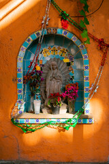 Small statue on religious altar on an orange wall