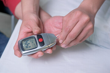 closeup on the hands of a latin woman doctor doing a test to measure sugar levels in middle-aged man as a prevention method to avoid suffering from diabetes