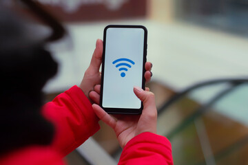Free internet in the supermarket. Woman holds a mockup of a smartphone with an icon on a white screen against the background of the escalator in the mall.