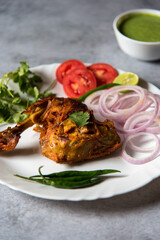 Close up of Coriander leaf on chicken tandoori leg piece on a plate with use of selective focus.