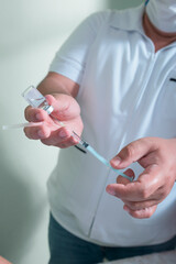 closeup to the hands of a latin man holding a syringe and medicinal liquid to be injected as a vaccine