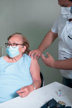 Health Personnel Middle-aged Latino Man Vaccinating Older Latino Woman In Times Of Pandemic