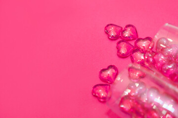 two glasses with hearts on a red background. the view from the top. red hearts spilled out of the glasses. isolated on a pink background. copy space