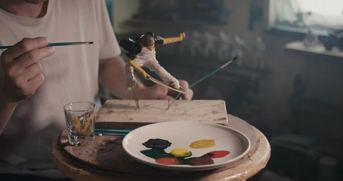 Artist paint skateboarder sculpture dip paintbrush atelier close up
