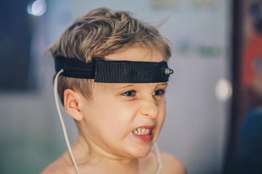 Express biofeedback microcurrent rezonans health of organs diagnostic. Sick child boy wear bioresonance head electrodes reveal disease causing bacteria via electromagnetic fields based on biofeedback