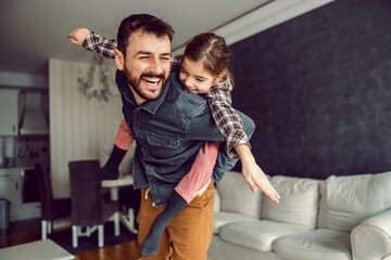 Smiling father and daughter playing together. They have piggyback ride.