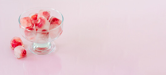 Obraz na płótnie Canvas Ice cubes with strawberries on pink background. banner.