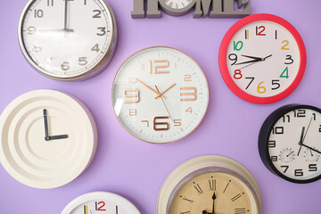 Different clocks hanging on color wall