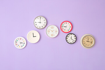 Different clocks hanging on color wall