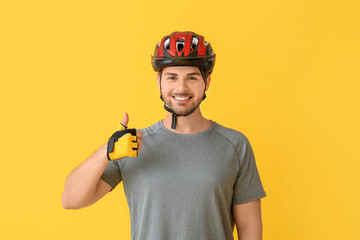 Male cyclist showing thumb-up on color background - obrazy, fototapety, plakaty