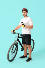 Male cyclist with bottle of water on color background