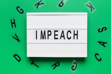 Board with word IMPEACH on color background
