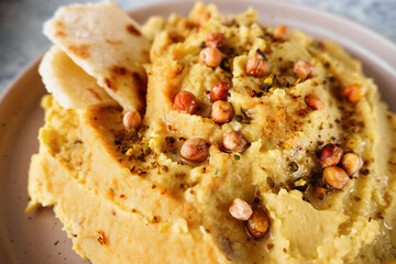 chickpea hummus with olive oil, garlic, spices and sprinkled with fried chickpeas, simple recipes for cooking at home, close up, selective focus