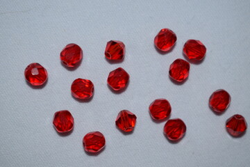 Large red beads scattered on a white background. Materials for needlework.