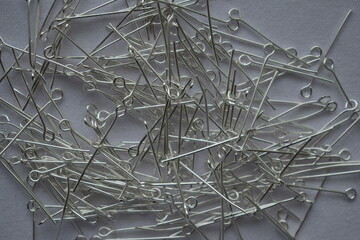 Silver metal pins on a white background. Materials for needlework.