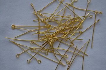 Gold metal pins on a white background. Materials for needlework.