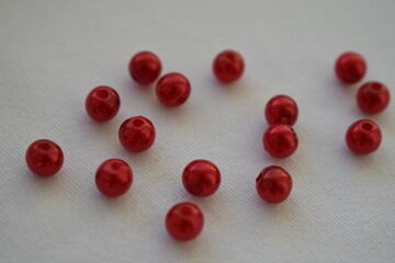 Red round beads scattered on a white background. Materials for needlework.