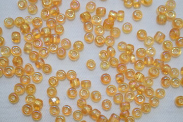 Yellow beads scattered on a white background. Materials for needlework.