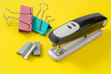 stapler, paper clips and clothespins lie on a yellow background