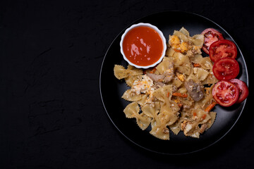 Macaroni in a black ceramic plate on a black table