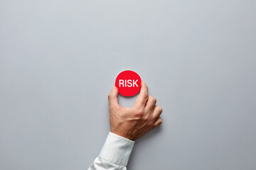 Businessman hand holding a red badge with the word risk. Risk assessment, financial risk or...