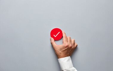 Businessman hand holding a red badge with a check mark. Approve, verify or confirm in business