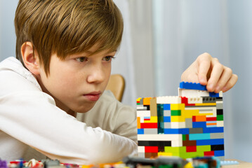 young boy playing with plastic construction toys at home.