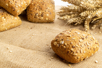 Bakery products. Rye bakery with crusty loaves and crumbs. Fresh loaf of rustic traditional bread with wheat grain ear or spike plant on natural cotton background. Concept - Cooking at Home.