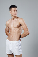 Fototapeta premium a man in white shorts holds his hands behind his back a look to the side inflated torso workout