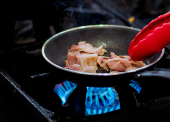fresh fried bacon in a pan, Chef cooking in the kitchen