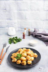 Traditional fried pelmeni, ravioli, dumplings filled with meat on black plate, russian kitchen. Gray concrete background, copy space.