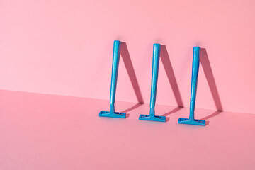 Obraz na płótnie Canvas Blue disposable razors on pink paper background
