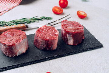 Raw veal medallions on black stone board