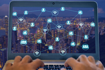 People using laptop to connect with other person with wireless networking diagram over cityscape at night that represent the internet communication in worldwild.