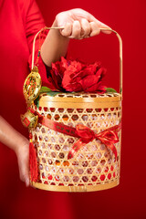 Chinese New Year concept, Woman holding Orange fruits bamboo basket on a red background, Have a healthy and wealthy in Chinese word.
