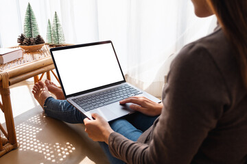 Mockup image of a woman working and touching on laptop touchpad with blank white screen at home