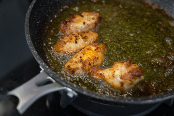 Pieces of chicken meat are frying in the kitchen pan, food preparation photo. Close-up and selective focus at some piece of the object.