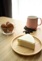 Piece of a creamy butter cake in wooden plate with coffee cup and egg for breakfast set. Homemade bakery concept for background and wallpaper.