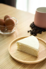 Piece of a creamy butter cake in wooden plate with coffee cup and egg for breakfast set. Homemade bakery concept for background and wallpaper.