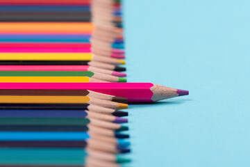 Fototapeta premium One pencil standing out from the group of other pencil on blue background