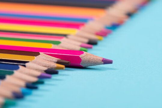 One pencil standing out from the group of other pencil on blue background